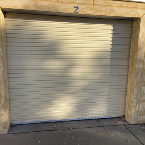Cream roller door on a single garage with a sandstone surround